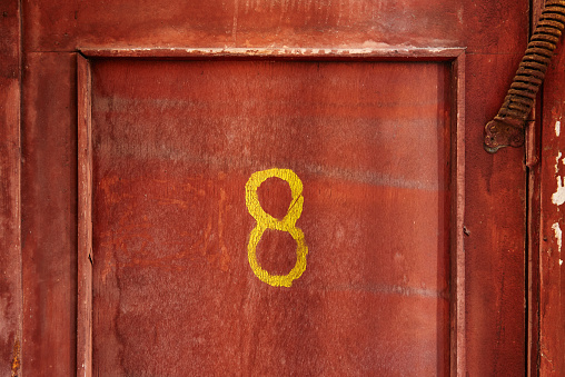 number eight written by paint on old red wooden door