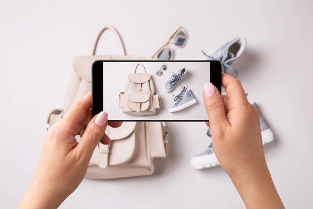 mujer tomando foto de mochila blanca y zapatillas azules con smartphone. influencer y redes sociales. - shopping bag fotos fotografías e imágenes de stock