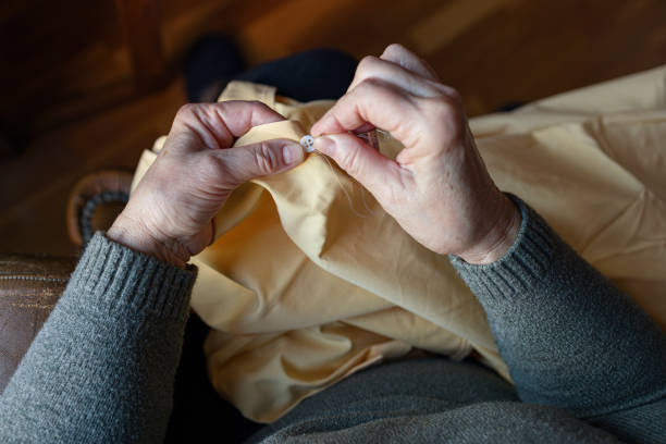 istock Old woman sewing a button at home 1385739155