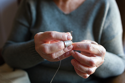 Old woman threading a needle