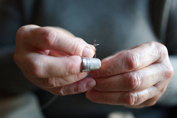 istock Close up of an old woman threading a needle 1385739356