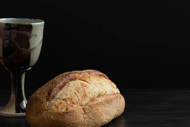 чаша и буханка ремесленного хлеба на черном - communion table стоковые фото и изображения