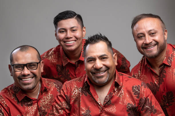 lächelnde vier hispanische männer, die auf grauem hintergrund in die kamera schauen - men latin american and hispanic ethnicity young men smiling stock-fotos und bilder