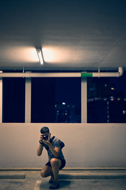 istock Young man using a camera in knee sitting for take a shot 1385743937