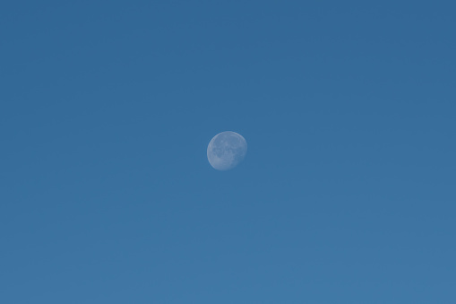 Moon in daytime against dark blue sky over Germany