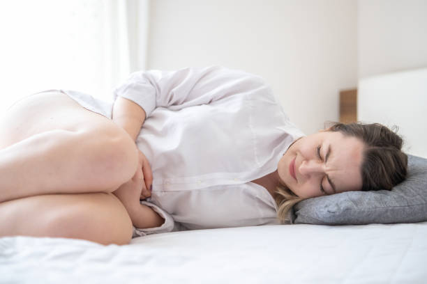 Young woman suffering from menstrual pain is holding her belly stock photo