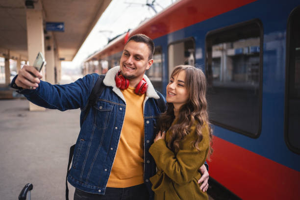 istock Young couple standing at the train station taking selfies while waiting for their train 1385748535