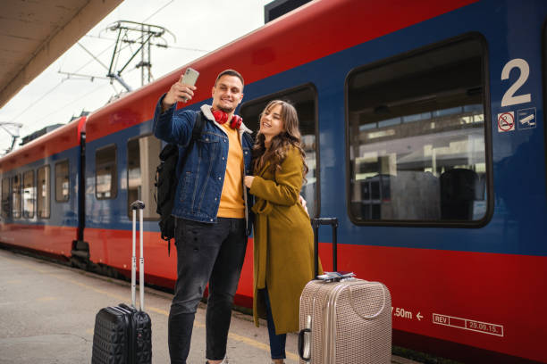 istock Young couple standing at the train station taking selfies while waiting for their train 1385748559