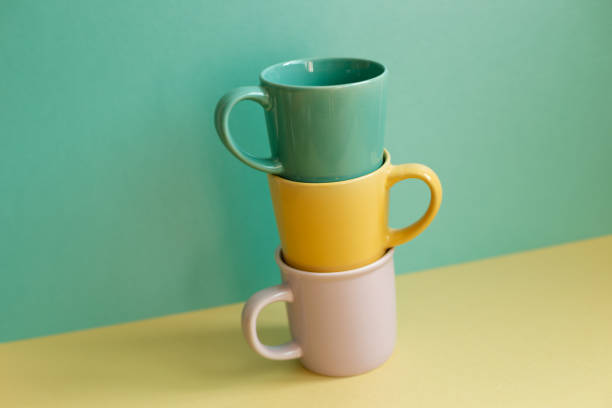 istock Stack of mug cups on yellow table. green wall background. home interior 1385751247