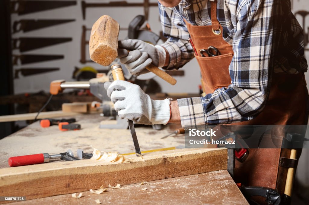 Skilled carpenter carving wood with hammer and chisel. Skilled carpenter carving wood with hammer and chisel. High quality photography Chisel Stock Photo