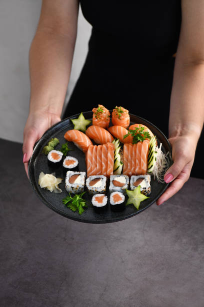 istock Woman hand holding a Sushi Mix plate 1385753992