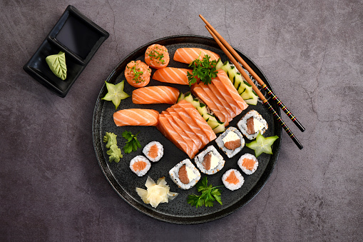 Concept of Asian cuisine. The girl is in a Chinese or Japanese restaurant sushi, holds wooden sticks in his hands. Dunk sushi in soy sauce. Different Asian dishes are on the table