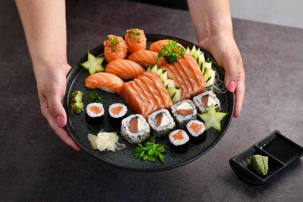 istock Woman hand holding a Sushi Mix plate 1385754906
