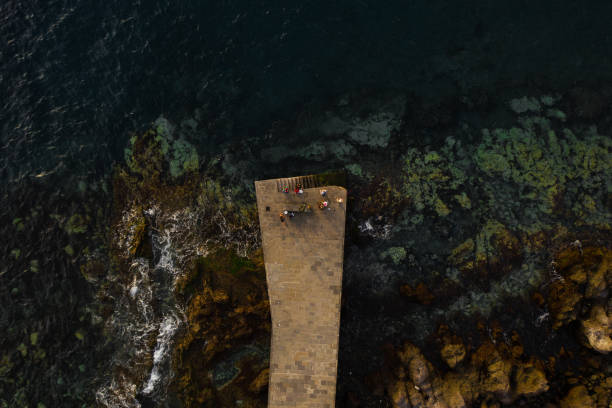istock fishermen on a stone pier catch fish surrounded by beautiful blue water. without faces 1385755441