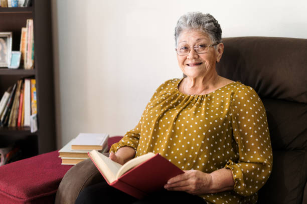 istock Happy senior woman sitting holding a book 1385761623