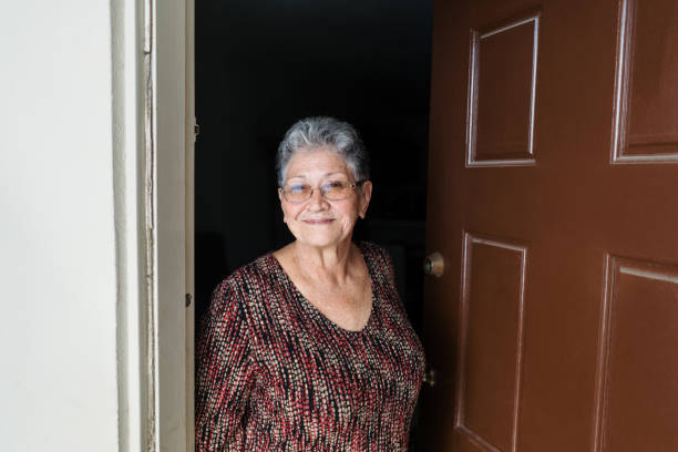 Smiling senior woman standing at doorway stock photo