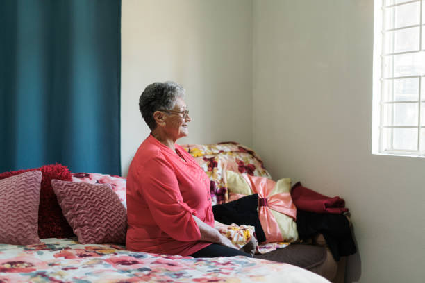 istock Elderly woman looking through bedroom window 1385761748