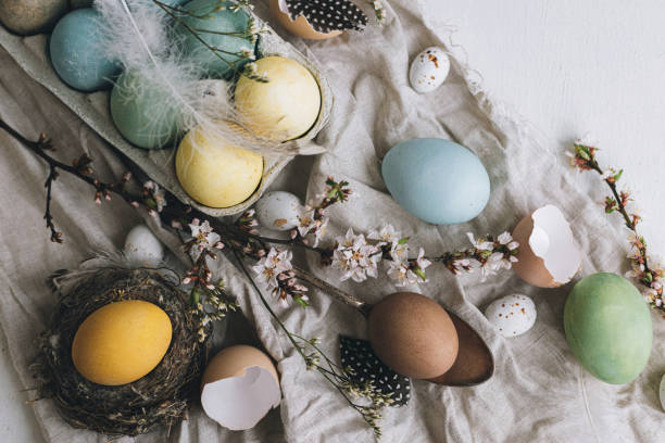 istock Happy Easter!  Stylish rustic Easter flat lay. Natural dyed colorful eggs, cherry blossoms, feathers and nest composition on linen cloth on white rustic table. Countryside still life 1385762908