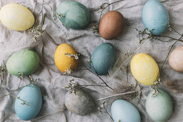 istock Happy Easter! Easter eggs on rustic linen napkin with tender flowers flat lay. Stylish natural dyed pastel colorful egg, spring flowers and feathers composition. Rustic still life 1385763294