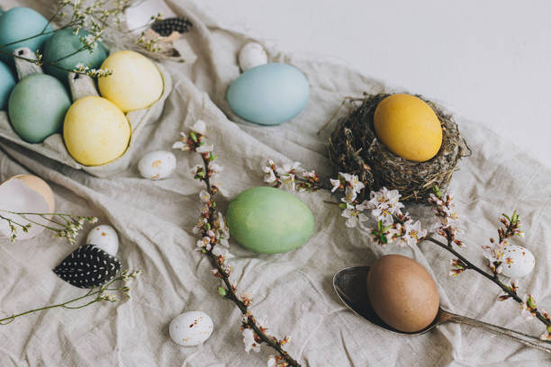 istock Stylish Easter eggs and cherry blossom on rustic linen background. Happy Easter!  Natural dyed colorful eggs, flowers, feathers and nest composition on rustic table. Countryside still life 1385763356