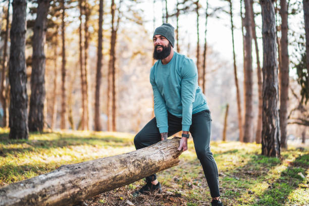 Sporty man is lifting tree stump stock photo