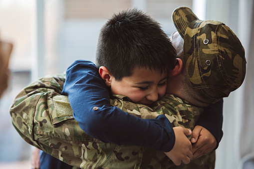 Soldier armed forces hugging his son at home - concept of family and war -