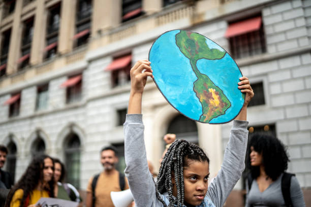 ragazza adolescente che tiene cartelli durante una manifestazione per l'ambientalismo - save the planet foto e immagini stock