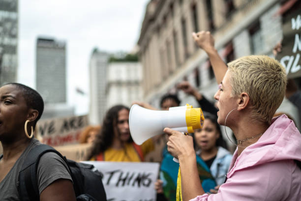 Woman shouting through megaphone during on a demonstration outdoors Woman shouting through megaphone during on a demonstration outdoors striker stock pictures, royalty-free photos & images