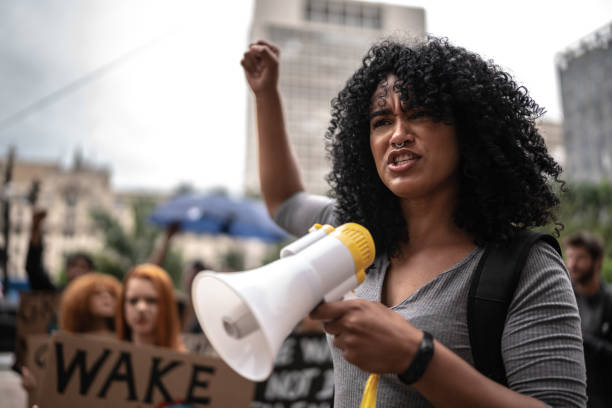 Young woman leading a demonstration using a megaphone Young woman leading a demonstration using a megaphone activist speech stock pictures, royalty-free photos & images