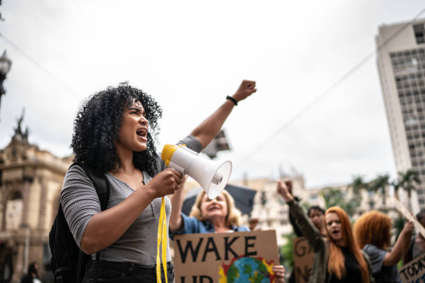 junge frau, die eine demonstration mit einem megaphon leitet - protest stock-fotos und bilder