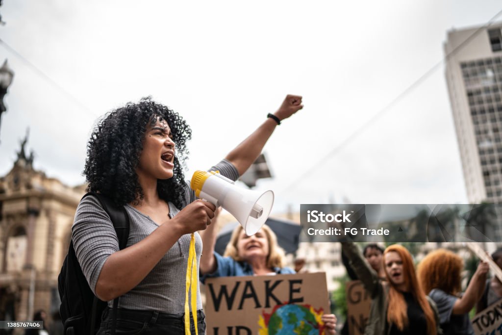 Young woman leading a demonstration using a megaphone Protest Stock Photo