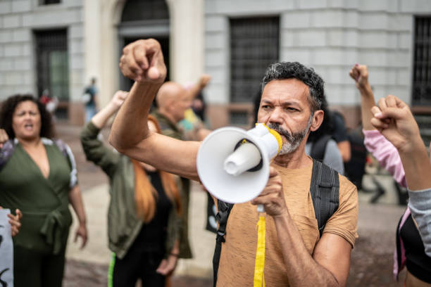 Mature man leading a demonstration using a megaphone Mature man leading a demonstration using a megaphone activist speech stock pictures, royalty-free photos & images