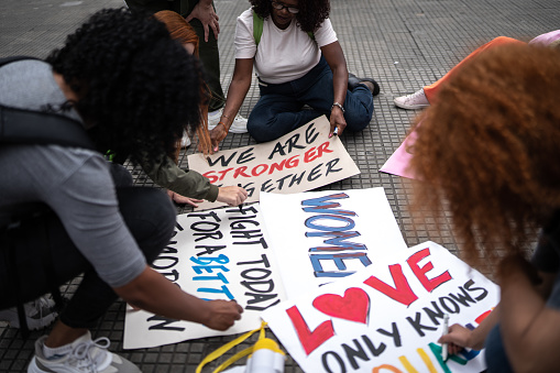 Women writing in posters before a protest in the street