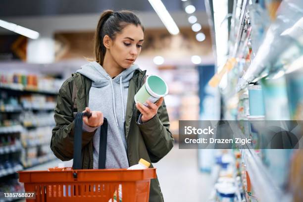슈퍼마켓에서 일기 제품을 구입하는 동안 영양 라벨을 읽는 젊은 여성 슈퍼마켓에 대한 스톡 사진 및 기타 이미지 - 슈퍼마켓, 쇼핑, 소매-소비자주의