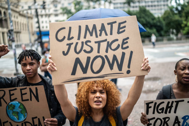 Mid adult woman holding a sign during a demonstration in the street Mid adult woman holding a sign during a demonstration in the street climate justice stock pictures, royalty-free photos & images