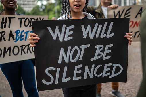 Low section of a girl holding a sign during a demonstration in the street