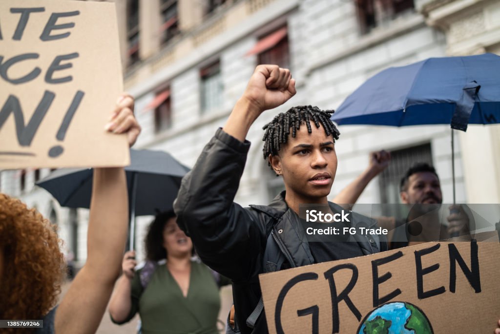 Young man holding a sign during a demonstration in the street Climate Stock Photo