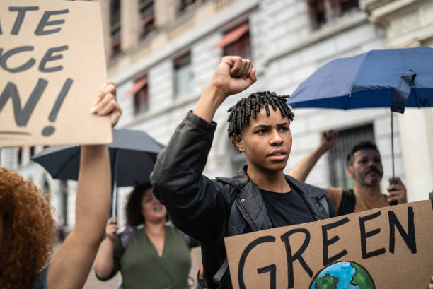 Young man holding a sign during a demonstration in the street Young man holding a sign during a demonstration in the street climate justice stock pictures, royalty-free photos & images