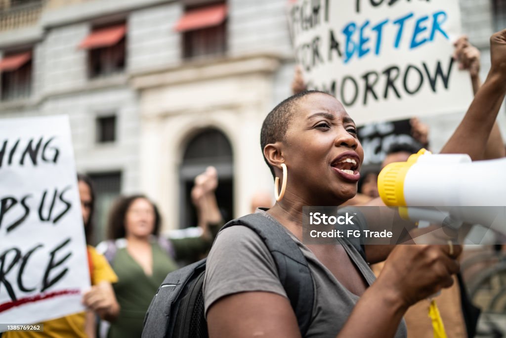 Mid adult woman leading a demonstration using a megaphone Rebellion Stock Photo