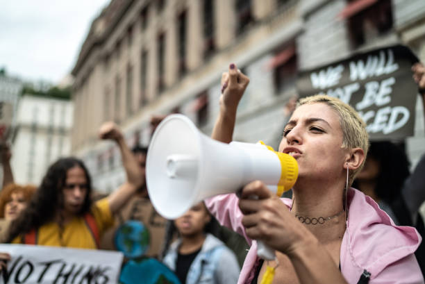 une jeune femme menant une manifestation à l’aide d’un mégaphone - manifestation photos et images de collection