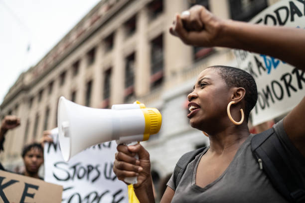 mujer medianamente adulta liderando una demostración usando un megáfono - protestor fotografías e imágenes de stock