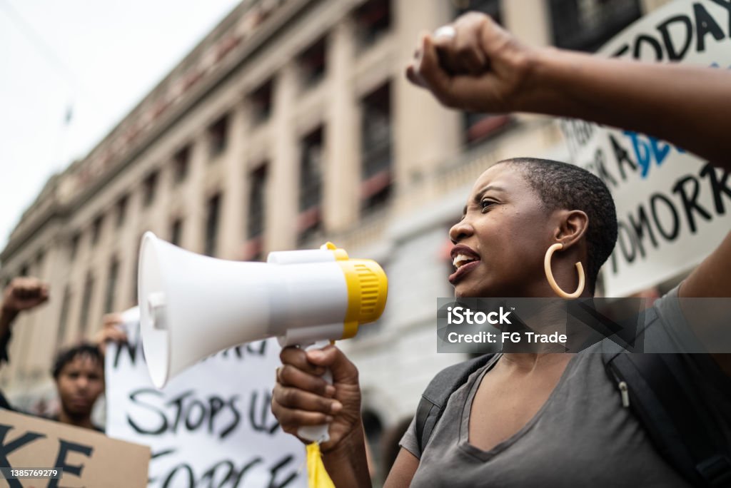 Mid adult woman leading a demonstration using a megaphone Protest Stock Photo