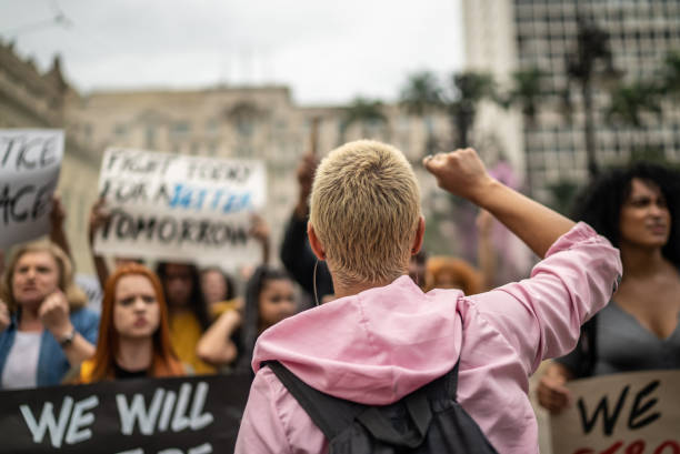 young woman leading a demonstration in the street - protesto imagens e fotografias de stock