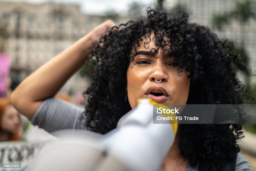 Woman leading a demonstration using a megaphone Portrait of a woman leading a demonstration using a megaphone Protest Stock Photo