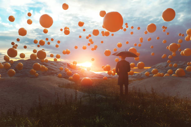 istock Surreal image of man standing in the field with falling spheres 1385778680