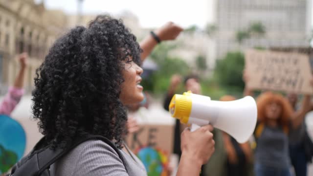 Portrait of a young woman leading a demonstration using a megaphone