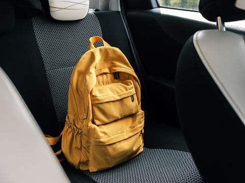 Yellow backpack inside car on back seat, travel concept.