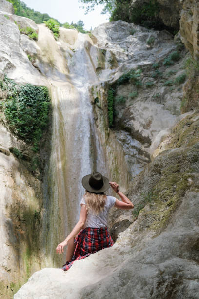 istock Young woman with hat sitting on a rock 1385783920
