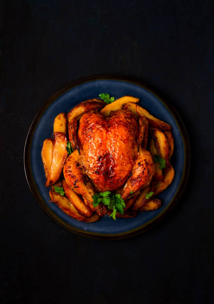 istock Fried whole chicken, with potatoes, on a black background, no people. 1385785100