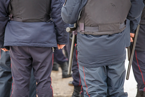 russian police officer in winter uniform with black rubber tonfa baton hanging on his belt, view from behind